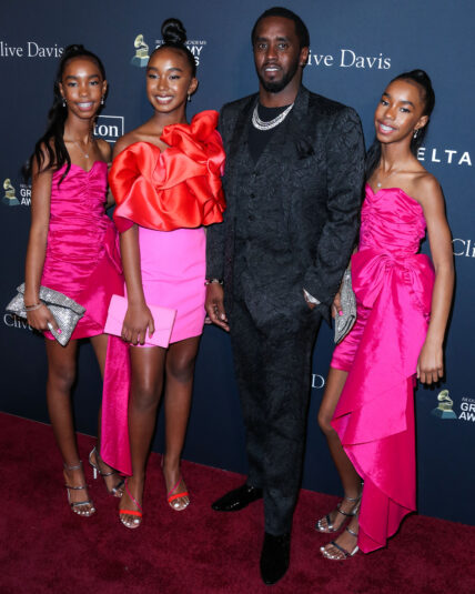 Diddy posing with his daughters on the red carpet.