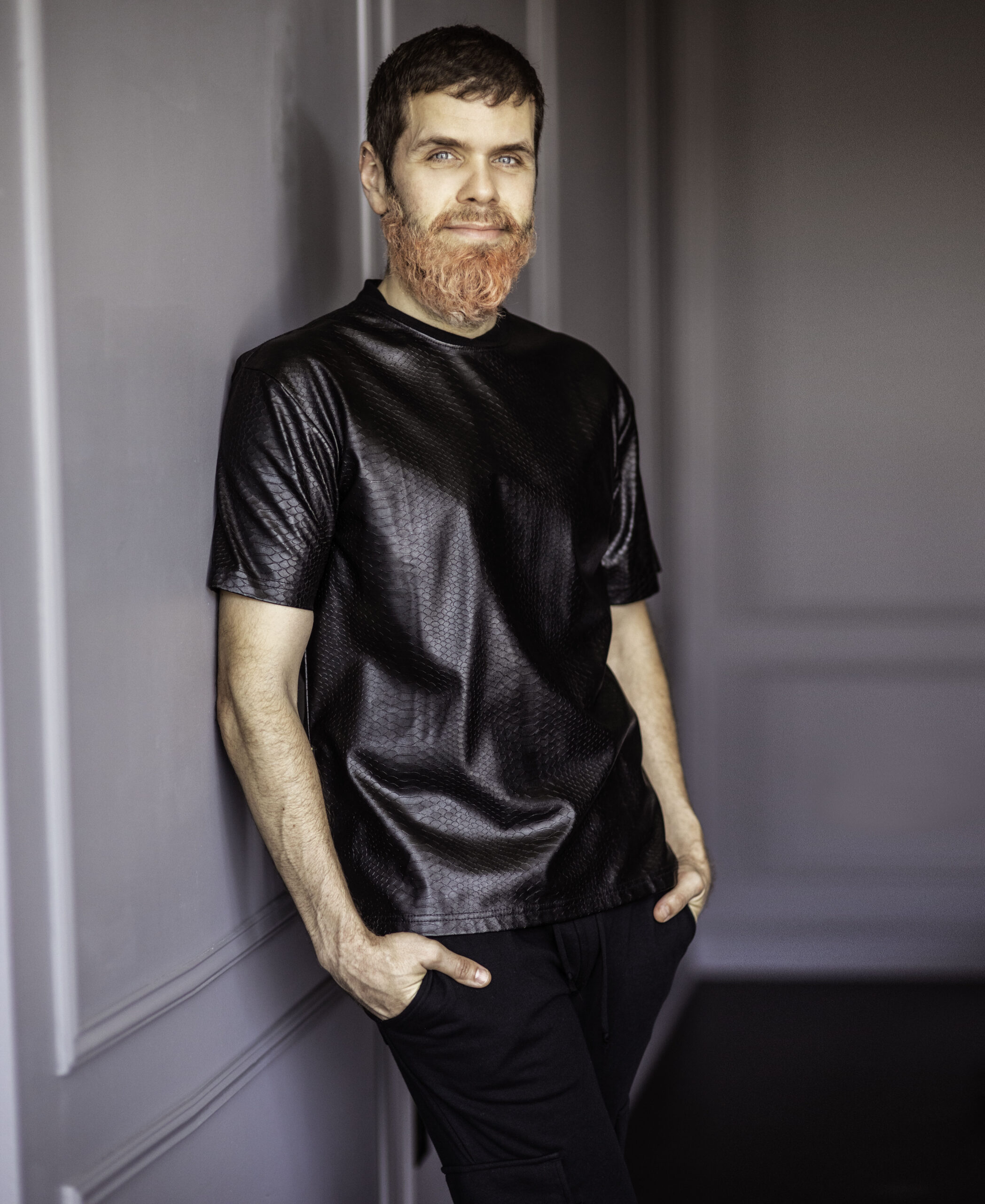 Perez Hilton leaning on wall
