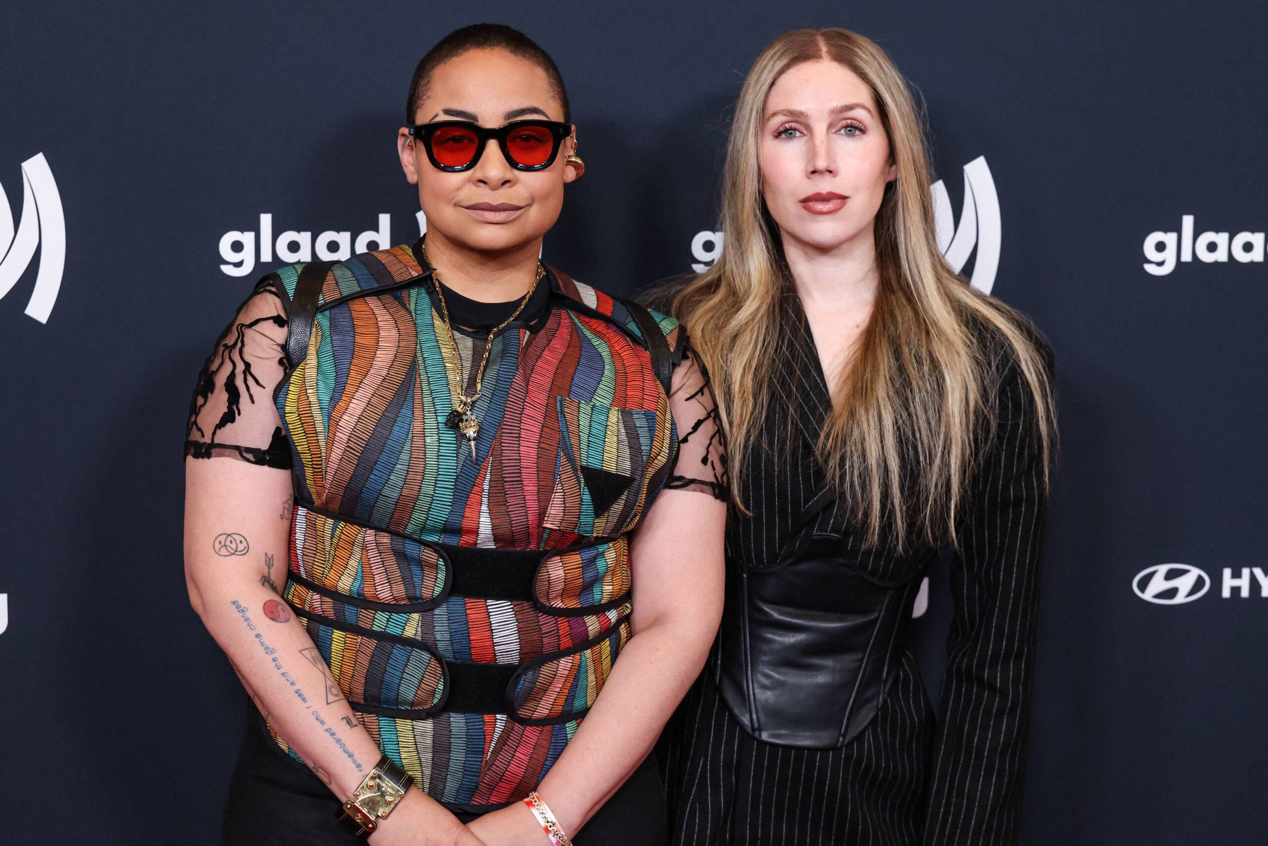 Raven Symoné and her wife posing on red carpet.