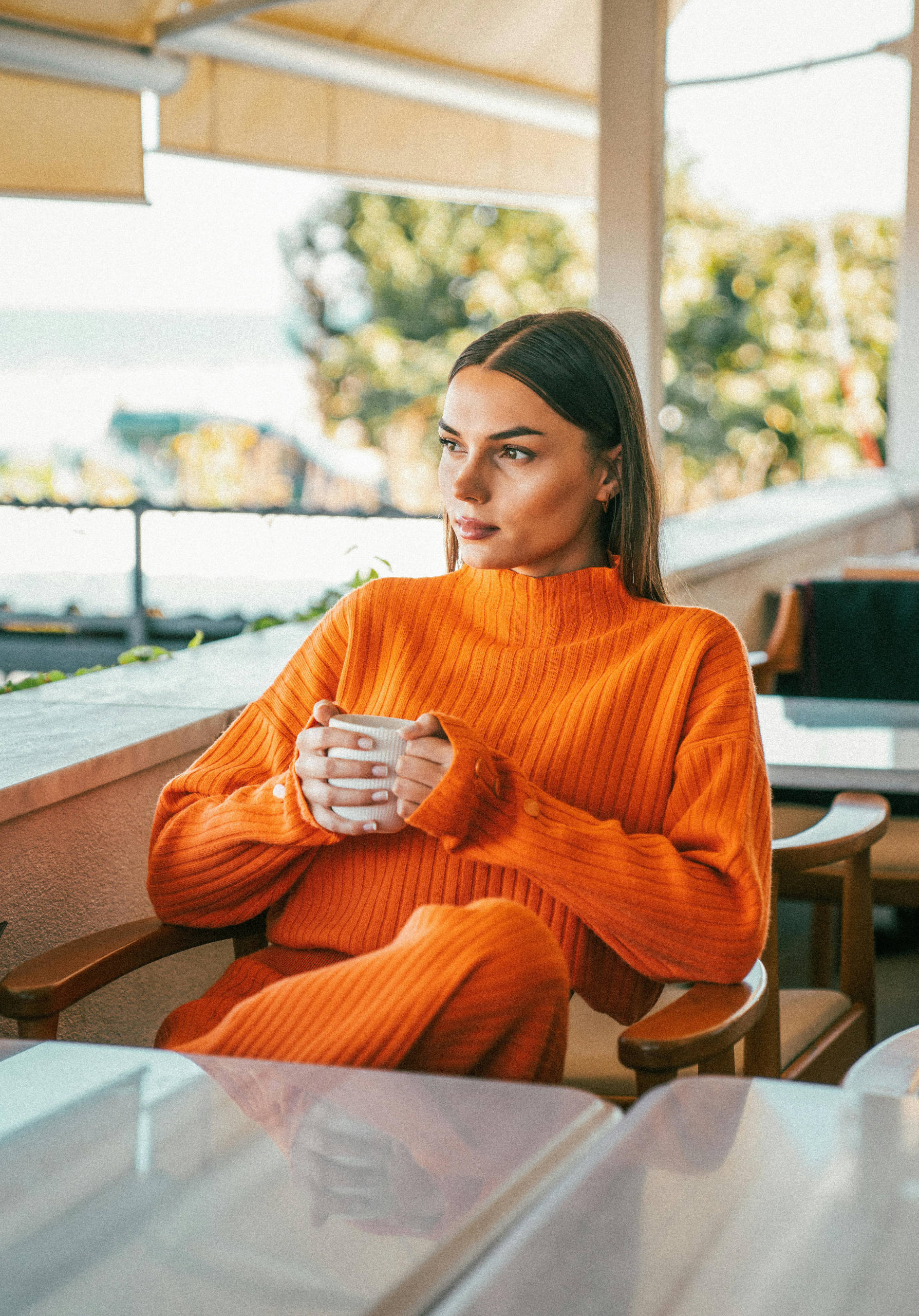Woman in orange outfit holding a cup of coffee