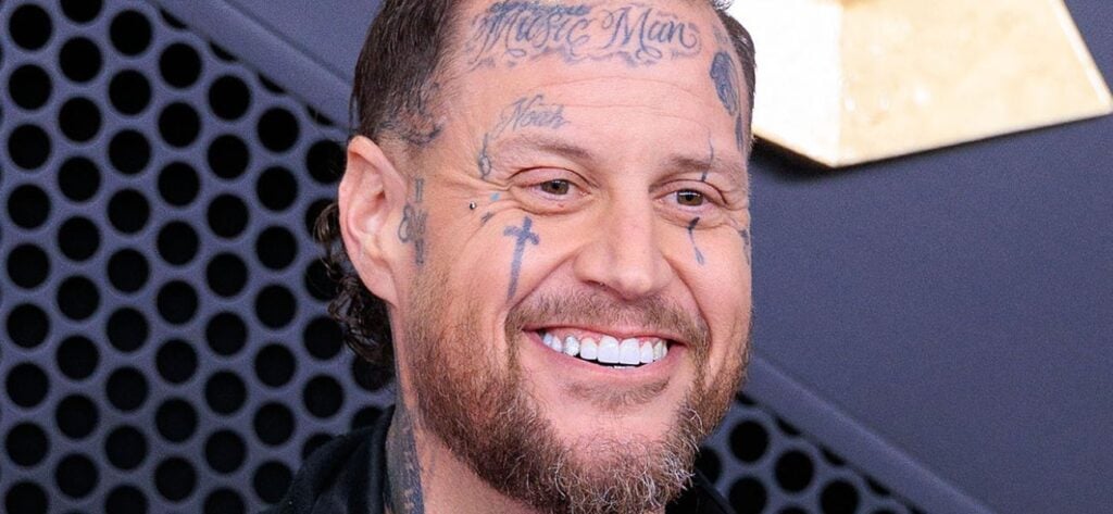 Jelly Roll smiling at an event with facial tattoos visible