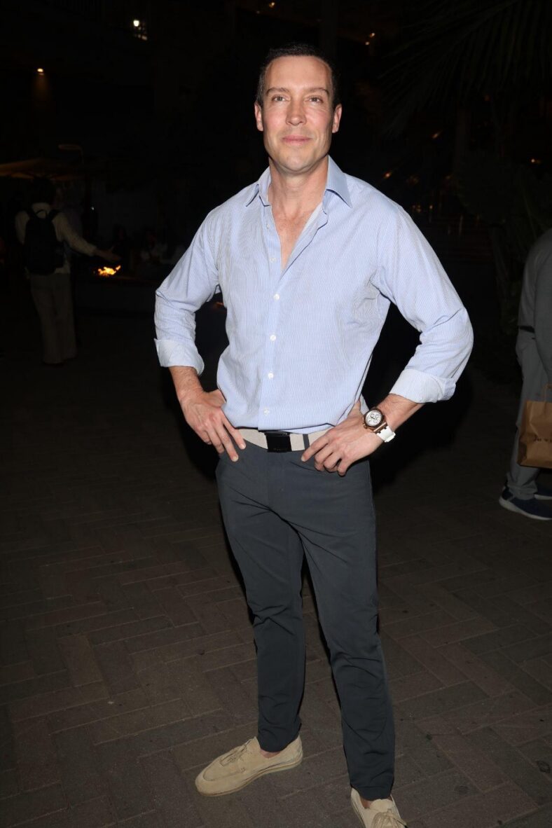 Man in jeans and blue shirt standing with hands on hips. 