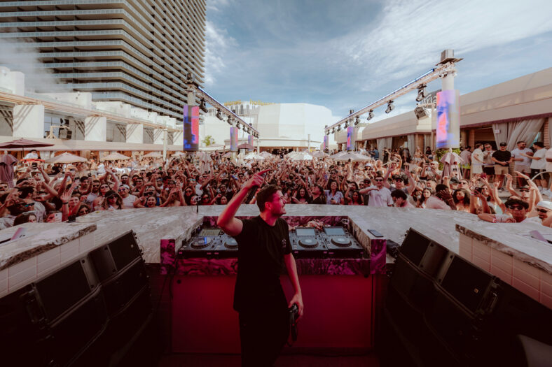 A DJ surrounded by a huge crowd of people.