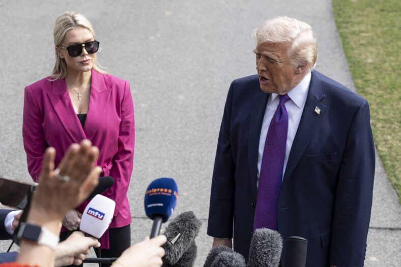 Donald Trump addressing reporters flanked by Karoline Leavitt.