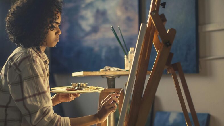 A woman sitting at an easel painting.