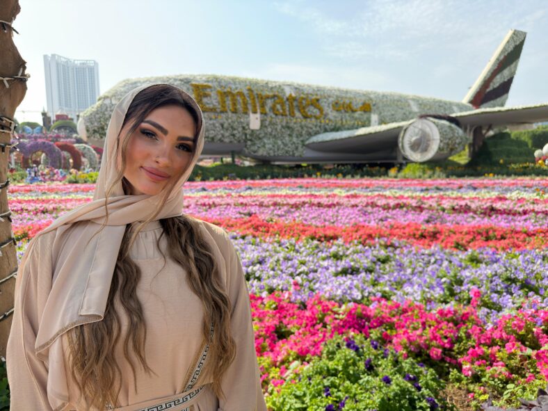 Woman posing in front of flower display.