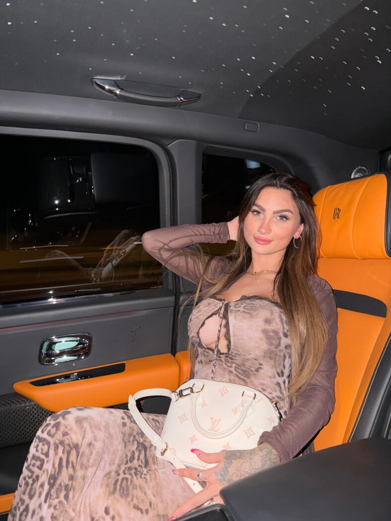 Woman posing in a car at night.