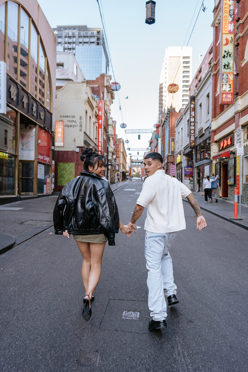 Man and woman holding hands, running away from camera. 