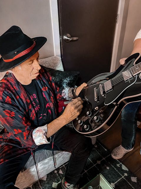 Keith Richards signs a guitar.