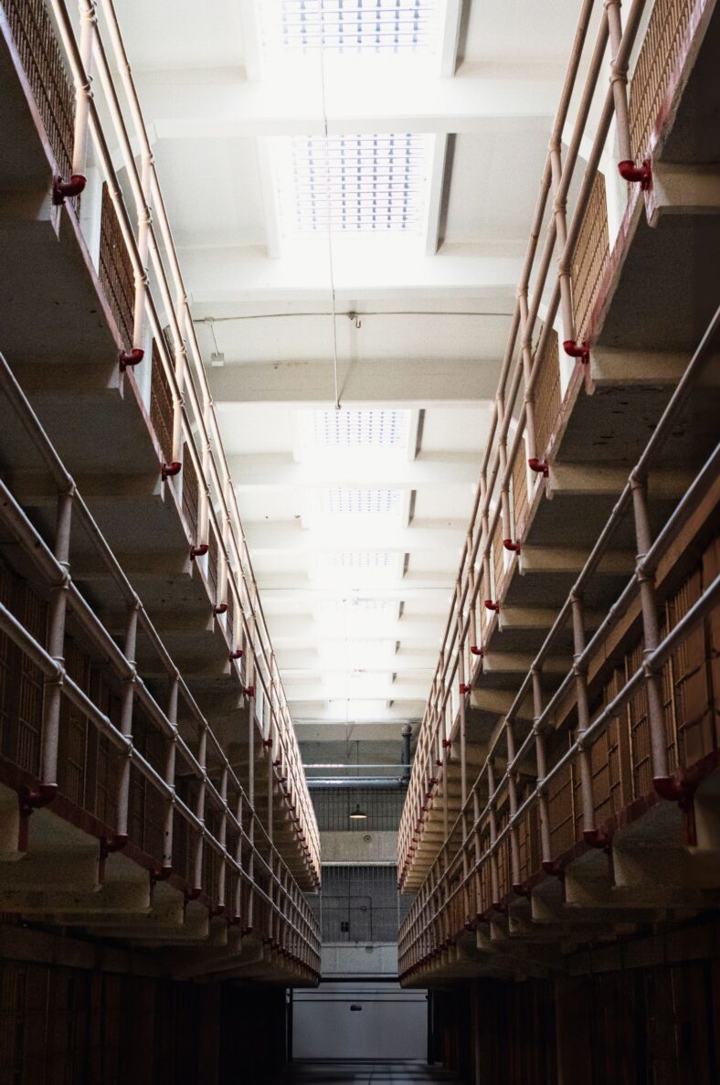Dramatic vertical shot of an empty prison corridor with railings and balconies
