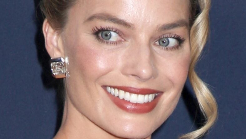 Margot Robbie ‘Struggles’ While Nearly ‘Popping Out’ Of Plunging Braless Dress