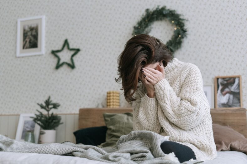 A sad woman sitting on a bed